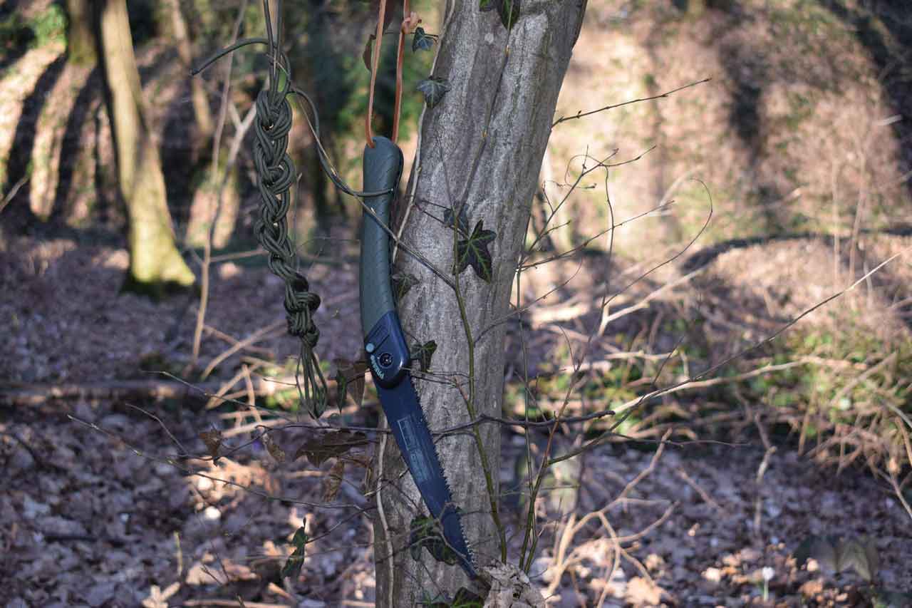 Bahco Laplander hanging on a tree in the woods with paracord daisy chain