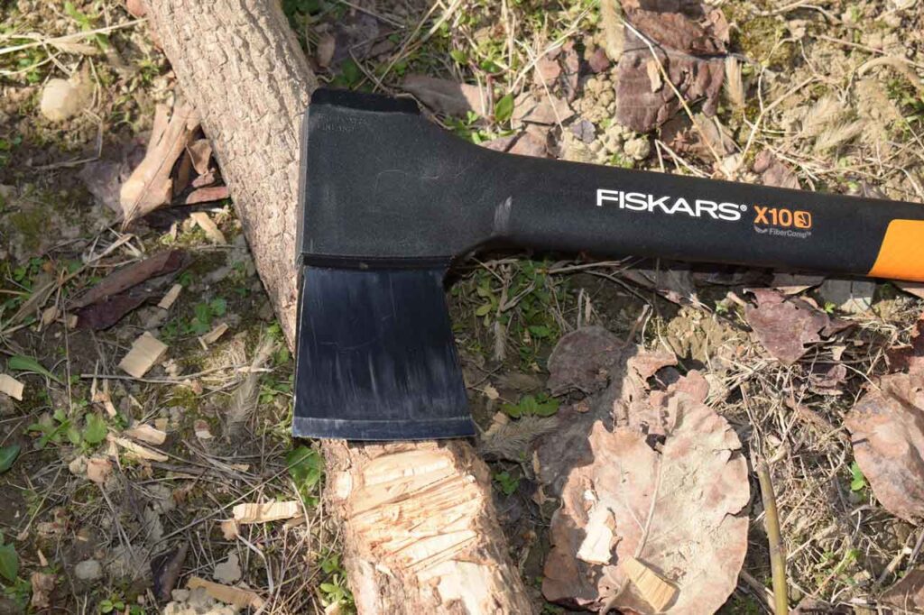 The 5 Best Survival Axes, Fiskars X10 Chopping Wood in the woods on a sunny day