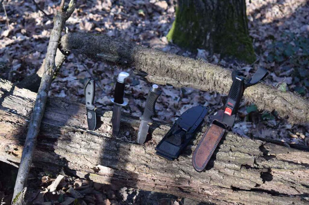 ESEE 3 , Buck 119 , Tekna Diving Knife with sheaths in the woods on a sunny day